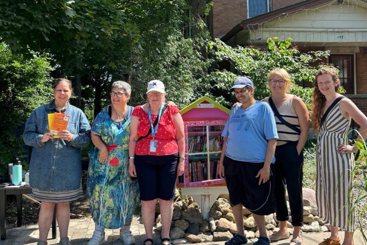 A group of six people are standing in front of the new Accessible Little Library