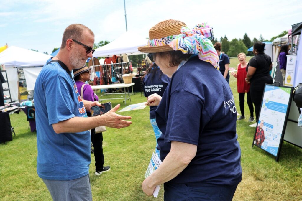 A volunteer is handing a flyer to the man