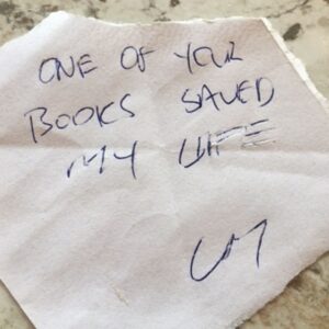 An anonymous note left in a book from the Accessible Little Library. The writing on the piece of paper says "One of your books saved my live".