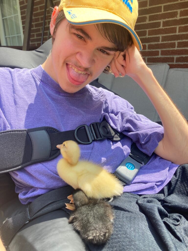 Russell, a person supported by CLGW, with two of the ducklings on his lap.