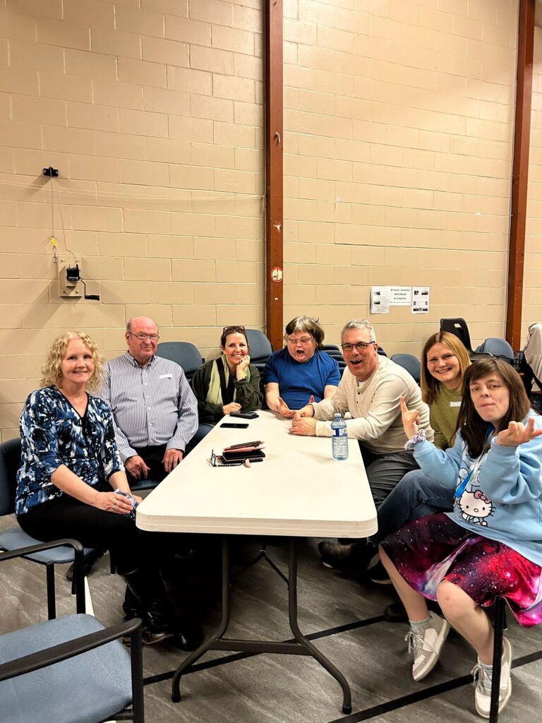 A group of people are sitting at a table at the CLGW Dance Party event